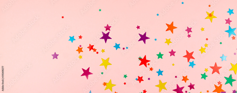 multicolored backdrop of colored stars confetti on a pink background