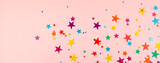 multicolored backdrop of colored stars confetti on a pink background