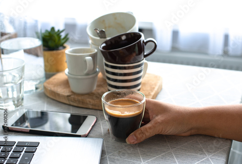 Quadro su tela A young female freelancer  working from home holding a cup of coffee with many c