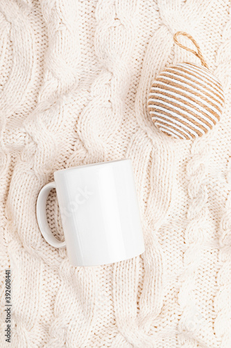 Mockup with white mug and eco friendly Christmas ornaments on knitted background. Assortment of cozy hygge Xmas decorations with copy space for text