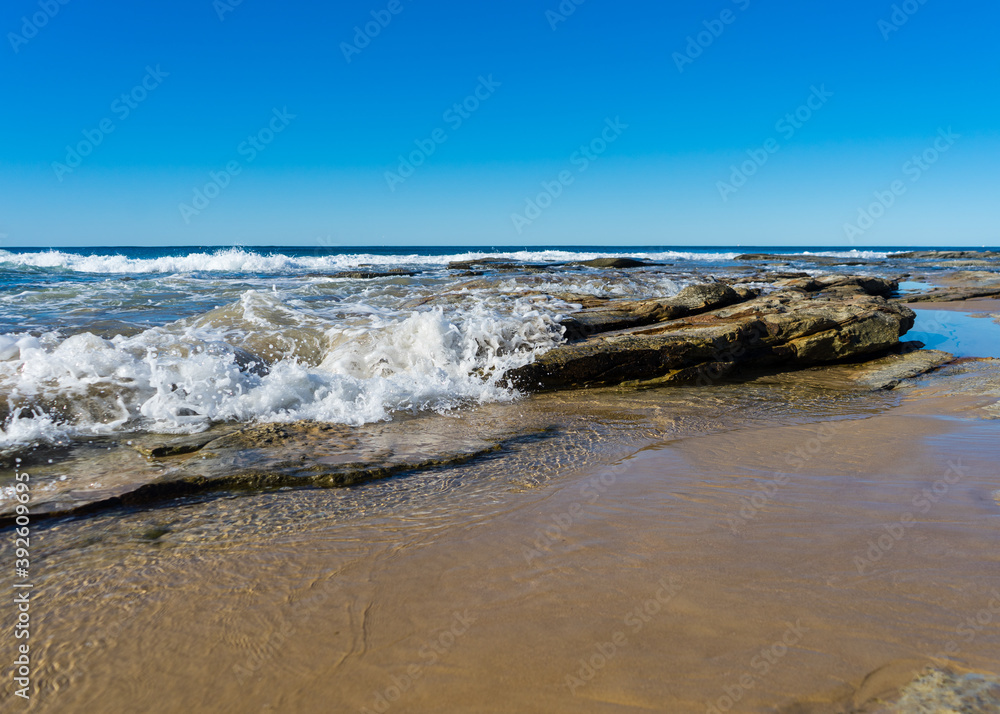 Fototapeta premium Photo of wave breaking over a rock on a summer day