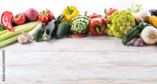 Different colorful vegetables arranged as a frame. Wooden background.