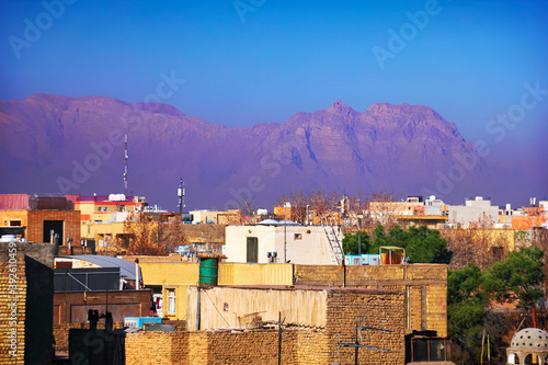 Beautiful city scape, old and modern houses at the background of purple barren mountain range, haze or smog and blue sky at evening, view from the roof, Isfahan (Esfahan), Iran (Persia), Middle East photo