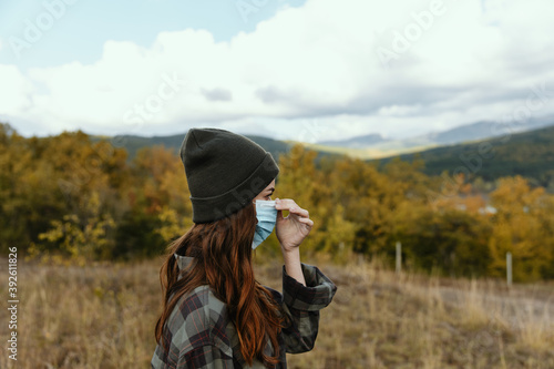Woman outdoors in the park in autumn with a medical mask on her face