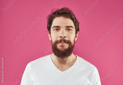 Handsome man with a beard and mustache on a pink background in a white T-shirt © SHOTPRIME STUDIO