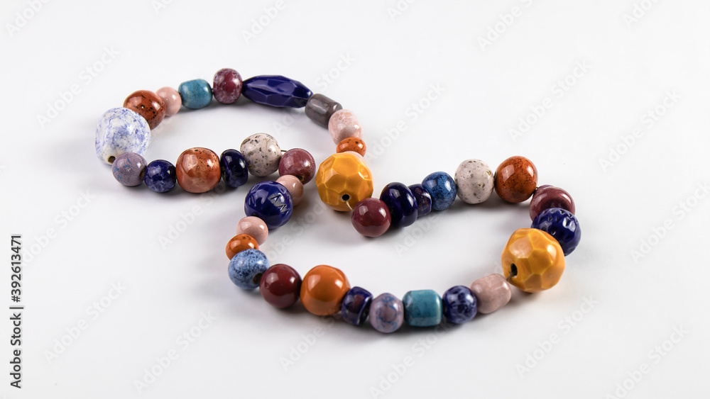 Isolated multi colored natural ceramic beads are on the white background. Traditional old Slavic culture.