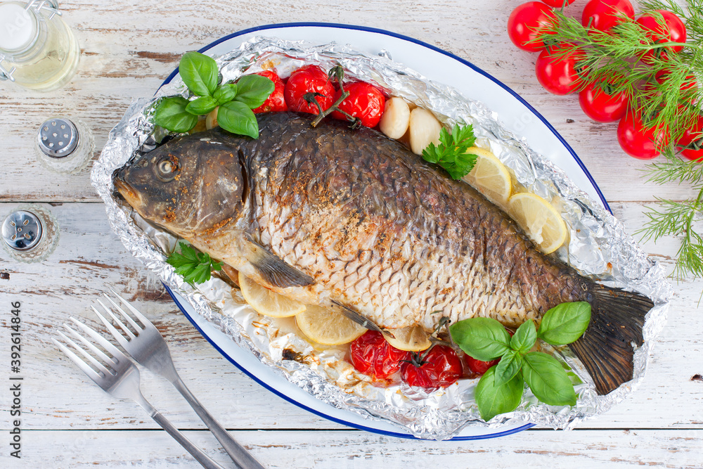 whole baked carp in foil with lemon in the oven, top view, horizontal whole baked carp in foil with lemon in the oven, top view, horizontal