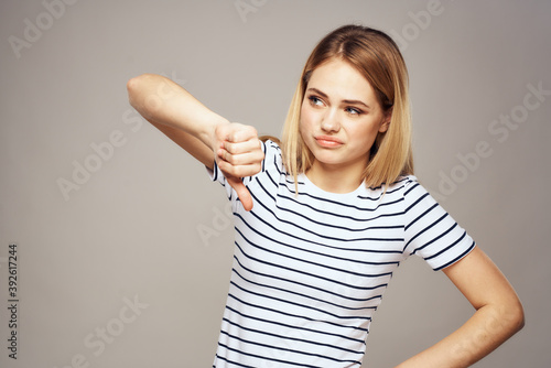 A woman with a displeased expression is gesturing with her hands T-shirt gray background