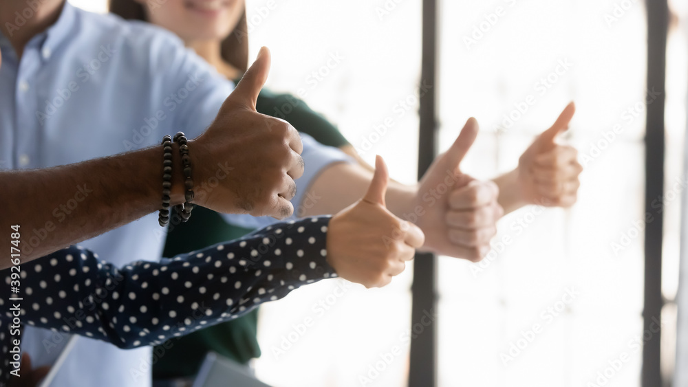 We all say yes. Close up shot of four young people workers clients of different gender ethnicity raising thumbs up showing general support acceptance recognition to company policy, service or product
