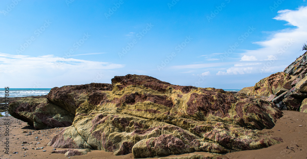 Vendée, FRANCE, green and brown and yellow rocks resembling camouflage on a beach in the town of Bretignolles Sur Mer.