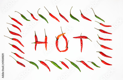 Word HOT made of Chili pepers isolated on white. Top view frame Layout of multicolor hot spicy peppers forming a word