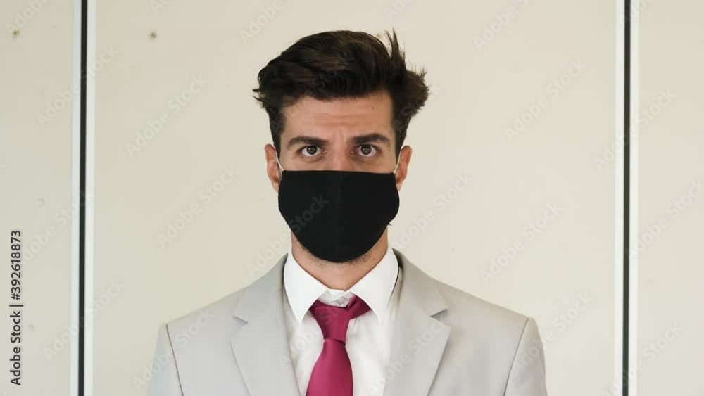 in the office with mask - serious manager wearing the mask looks at camera in the office with mask - serious manager wearing the mask looks at camera