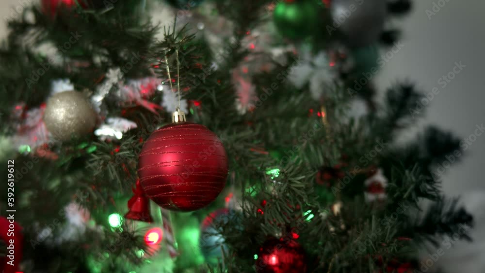 Close-up of man's hands decorating Christmas tree with balls on the background of bright festive lights. Decorating a Christmas tree with ornaments and lights. Close-up of man's hands decorating Christmas tree with balls on the background of bright festive lights. Decorating a Christmas tree with ornaments and lights.