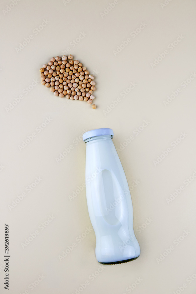 Chickpea vegetarian milk in a bottle, raw chickpeas  on light background. Non-dairy lactose free milk. Top view.