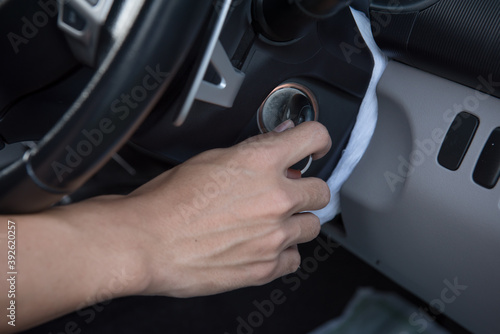 A man driver hand inserting car key and starting engine