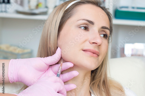 young woman receiving cosmetic injection. Woman in a beauty salon. Plastic Surgery Clinic.