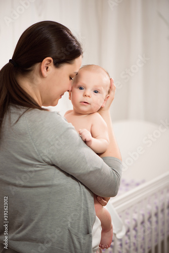 Young mother hugging her newborn child. Love, trust and tenderness concept. Bedding and textile for nursery.