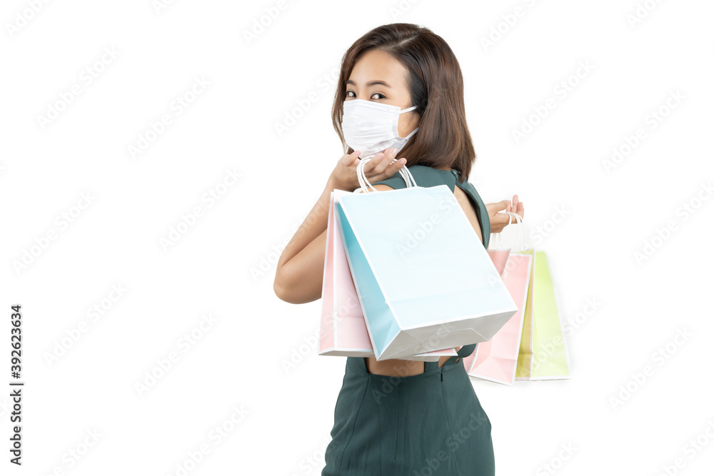 Young Asian woman holding shopping bag wear face mask on white isolate background .Enjoy Happy Shop Covid-19 concept Young Asian woman holding shopping bag wear face mask on white isolate background .Enjoy Happy Shop Covid-19 concept