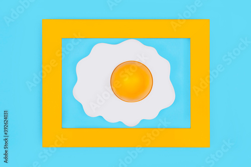 Fried egg in yellow frame on pastel blue background,minimal koncept