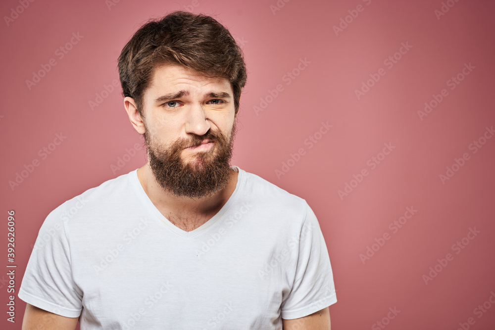 Obraz premium emotional man white t shirt sad facial expression pink background