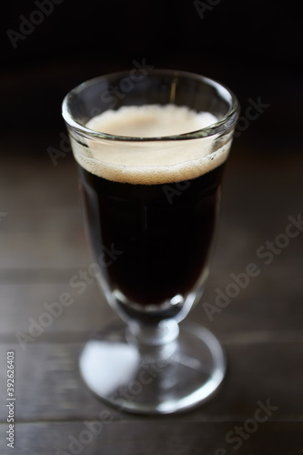 Glass of dark beer on dark wooden background. close up. 