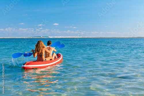Young women have fun on boat walk. Girls paddling on kayak by sea lagoon. Travel lifestyle, recreational activity, watersports on summer beach family vacation. © Tropical studio