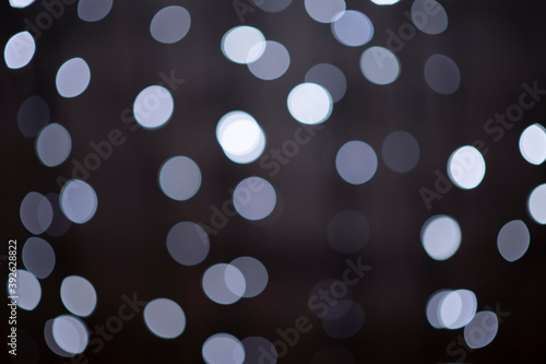 beautiful black and white festive bokeh background made up of white out of focus lights on dark background