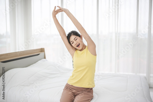 Young woman wake up in the morning and stretching on her bed 