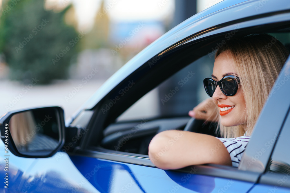 Naklejka premium Confident and beautiful woman in sunglasses. Rear view of attractive young female in casual wear driving a car