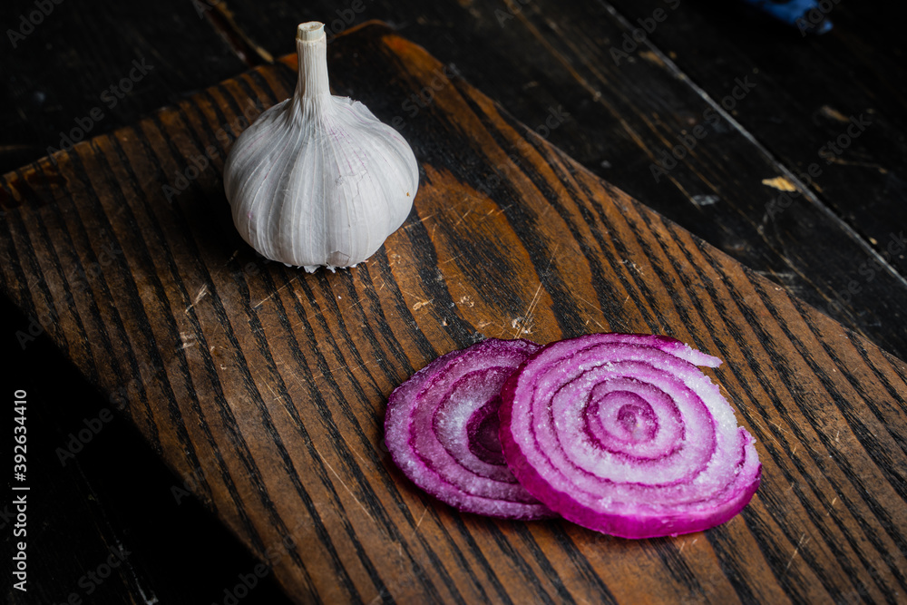 Onion, garlic and salt on a wooden cutting board. Top view. Onion, garlic and salt on a wooden cutting board. Top view.
