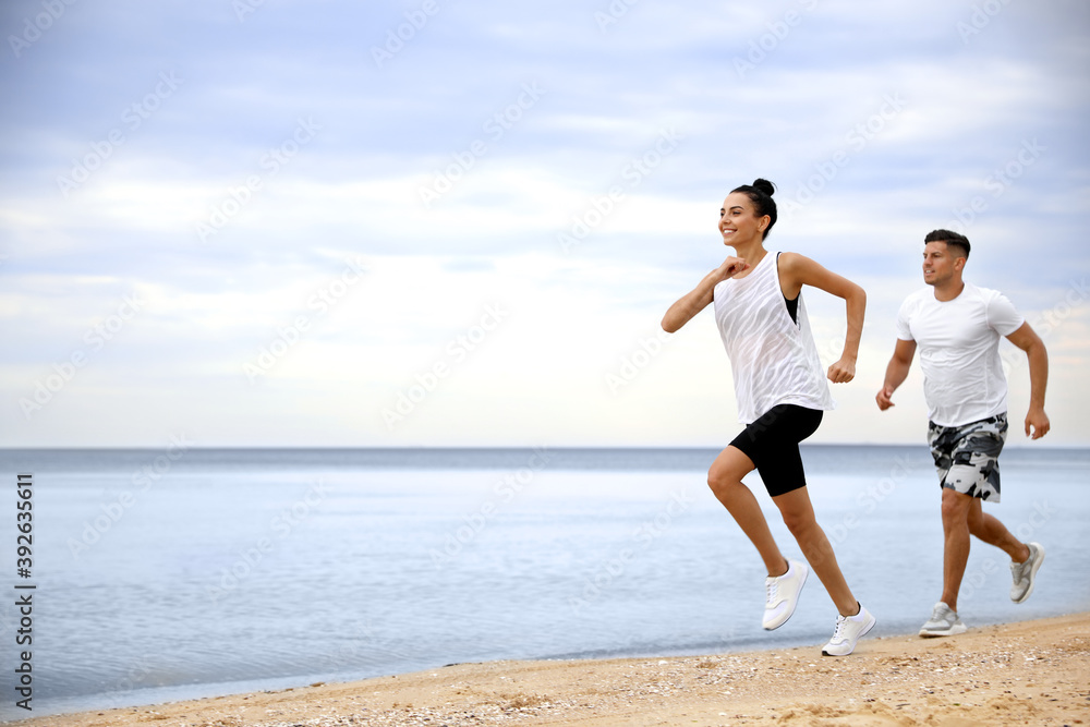 Couple running together on beach, space for text. Body training Couple running together on beach, space for text. Body training