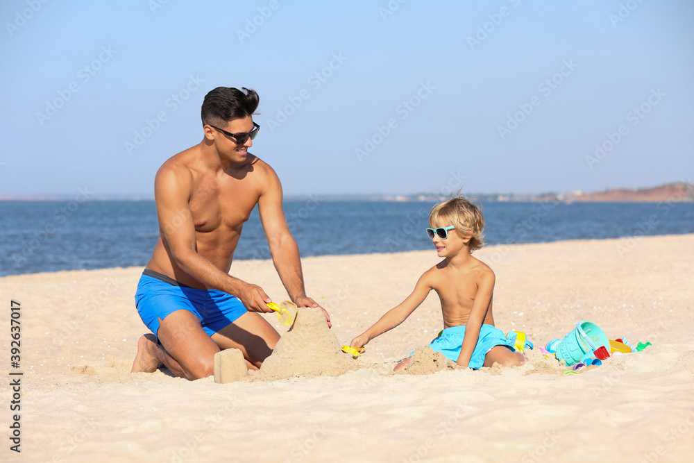 Father and son playing on sandy beach near sea. Summer holidays with family Father and son playing on sandy beach near sea. Summer holidays with family