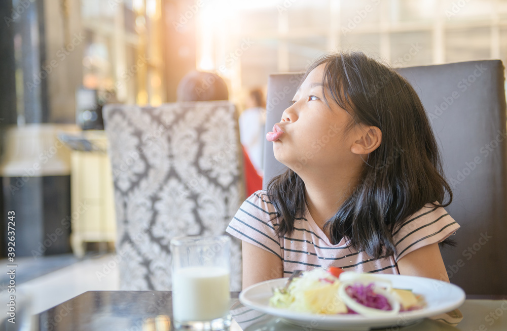 asian child girl with expression of disgust against vegetables in restaurant, asian child girl with expression of disgust against vegetables in restaurant,