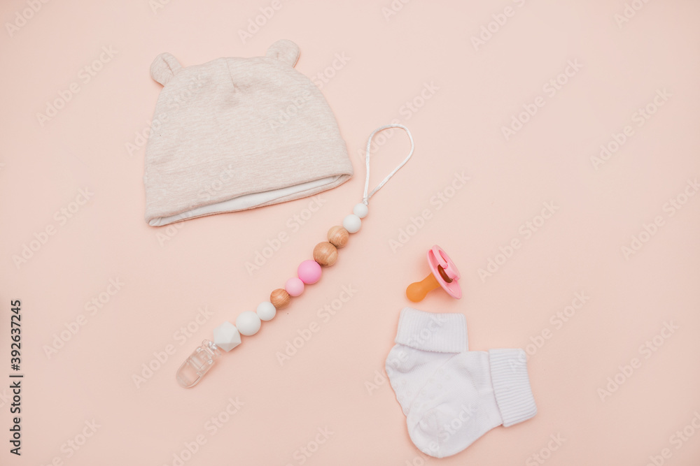 Fototapeta premium Clothes for a newborn girl: a tiny pink hat, cotton pants on a light background. baby clothes on the table. Children's fashion. clothes for newborns for girls. modern kids clothing store top view