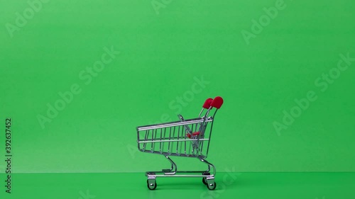 4k stop motion close-up of red shopping trolley with green background, cart running from the supermarket.