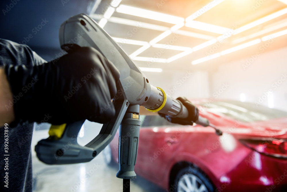 Worker washing car with high pressure water at a car wash. Worker washing car with high pressure water at a car wash.