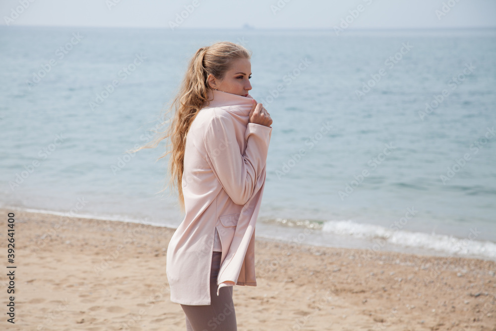 Beautiful blonde woman walks on an empty beach near the sea alone Beautiful blonde woman walks on an empty beach near the sea alone