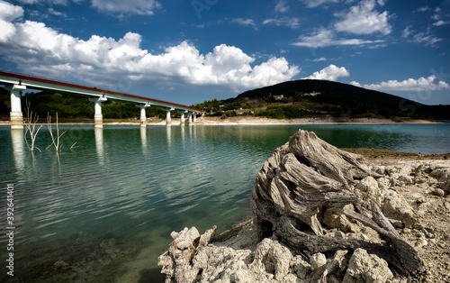 Beautiful panoramics views of Lake Castreccioni-Cingoli, with a landscape of clouds, water, grass, and mountains in summer.