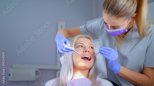 Dentist Examining Teeth With Medical Instruments Portrait Of Woman Checking His Teeth Professional Dentist Working With Gloves With Patients Teeth With An Open Mouth. Medical Stomatology Concept