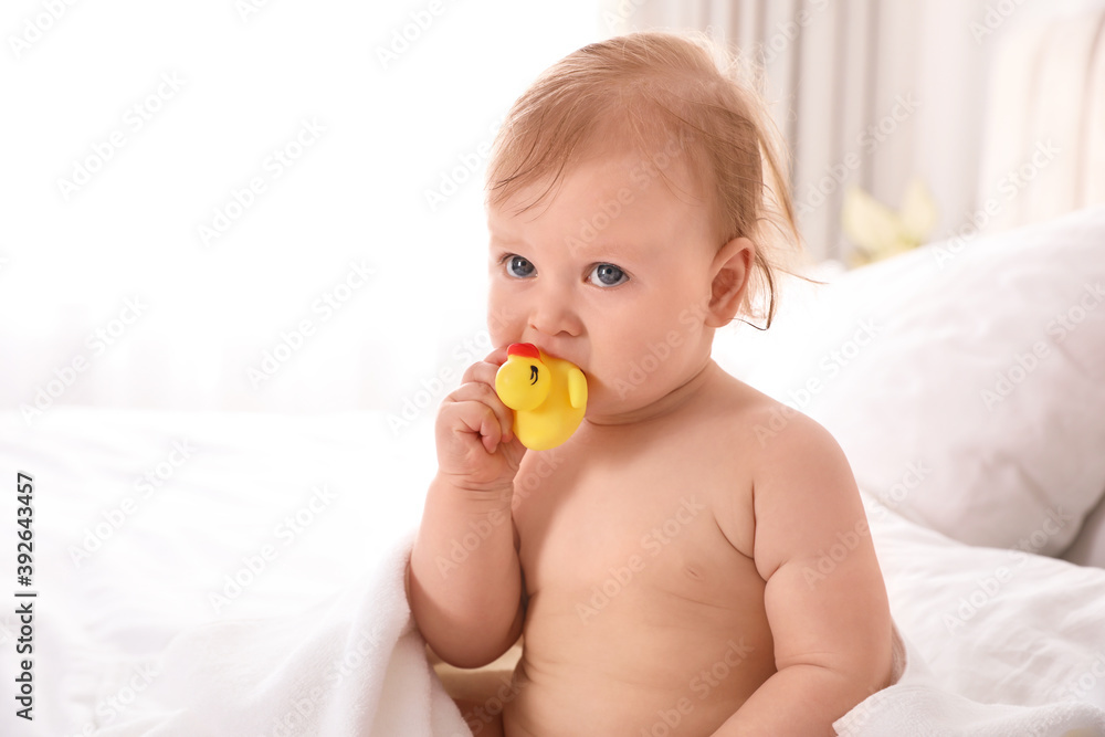 Cute little baby nibbling toy on bed after bath Cute little baby nibbling toy on bed after bath