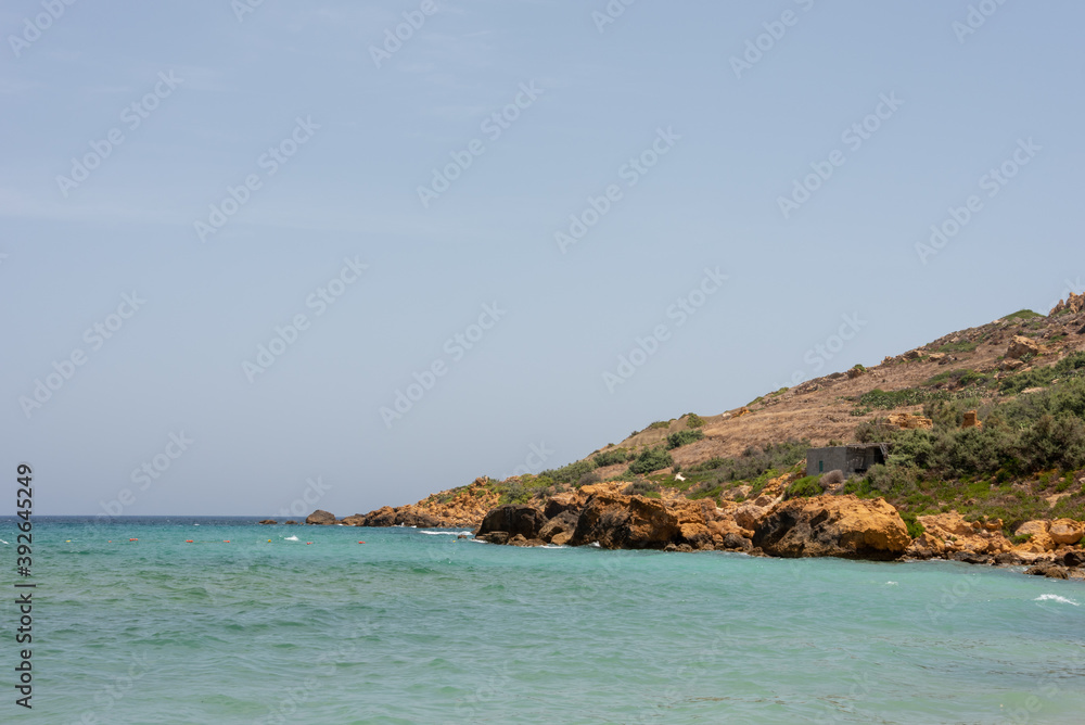Mediterranean Sea shore under blue sky. Ramla Bay beach, Gozo Island, Malta. Selective focus. 