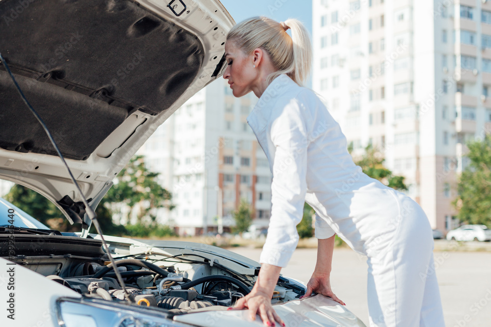 Beautiful female blonde mechanic repairs car engine