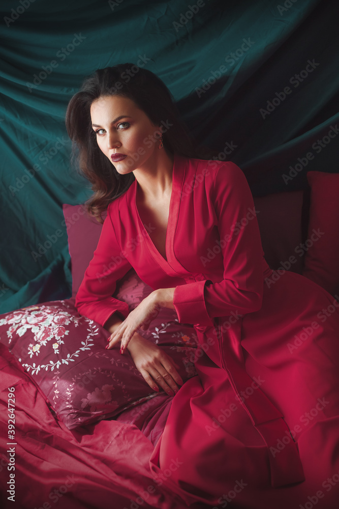 Fototapeta premium Portrait of beautiful young woman with makeup in red dress. Fashion photo