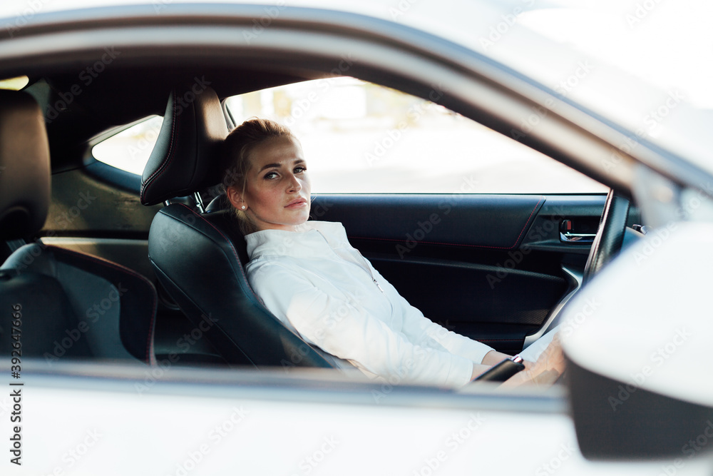 Beautiful female blonde driver behind the wheel of a car on the road