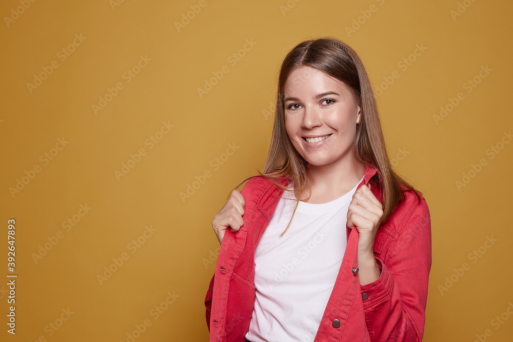 Happy smiling Caucasian woman demonstrates plain white t shirt, shows copy space for slogan or promotion, has natural shiny hair, satisfied expression, models oniced mango wall. Clothing and advert.. Happy smiling Caucasian woman demonstrates plain white t shirt, shows copy space for slogan or promotion, has natural shiny hair, satisfied expression, models oniced mango wall. Clothing and advert..