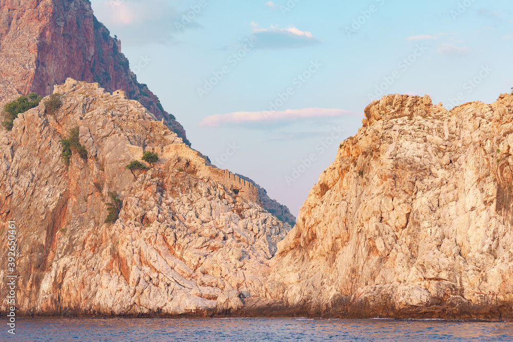 Orange slopes of mountains on calm sea with beautiful sky on background