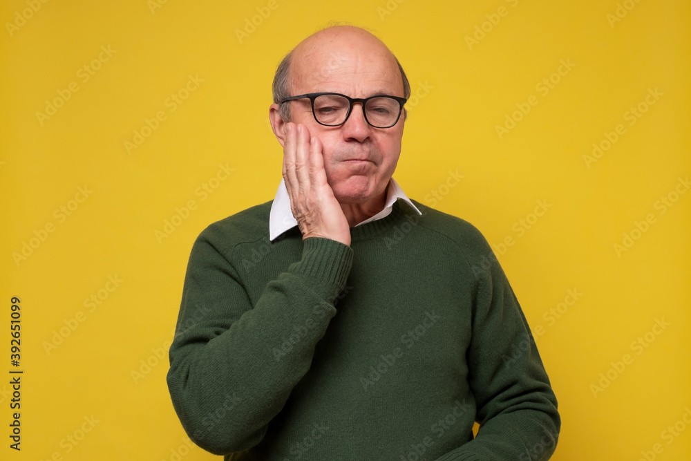 Old hispanic man having a toothache against yellow background Old hispanic man having a toothache against yellow background