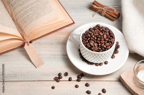 Coffee background with grains poured into a Cup and a book on a light background. Side view.