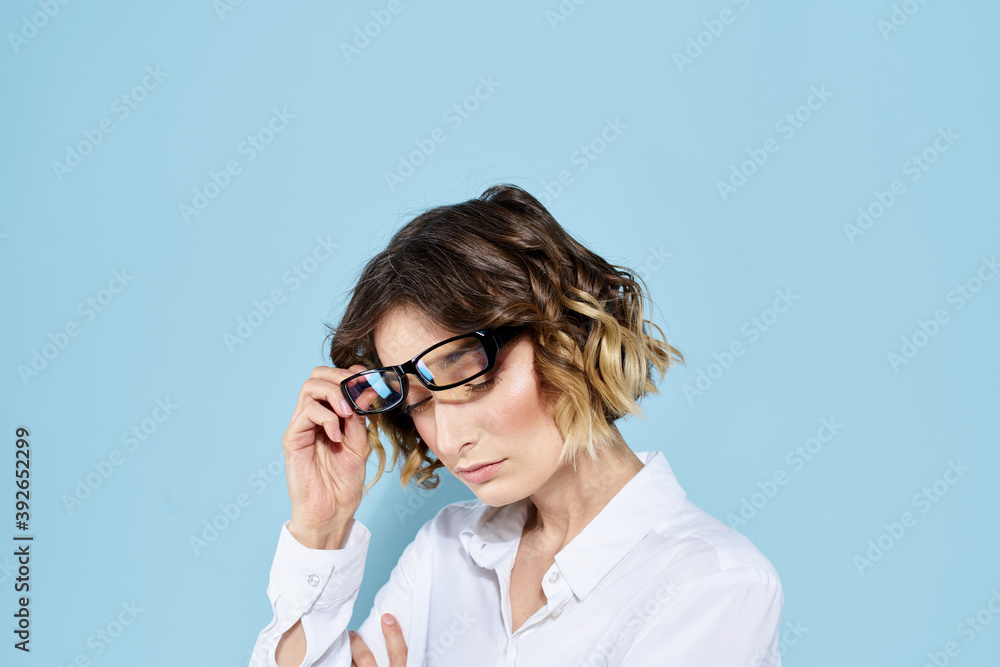 Business woman on a blue background glasses with dark rims curly hair Light shirt cropped view Business woman on a blue background glasses with dark rims curly hair Light shirt cropped view