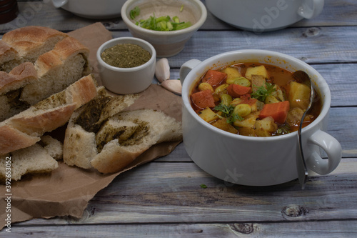 Potato, carrot and lima beans soup in white bowls on wooden backround, served with herb bread